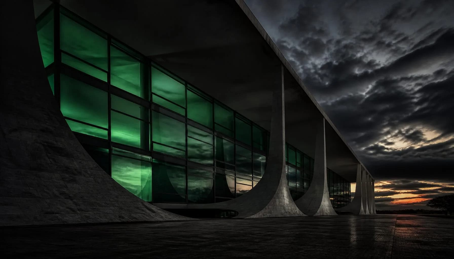 Arquitetura governamental moderna ao anoitecer, com reflexos verdes no vidro